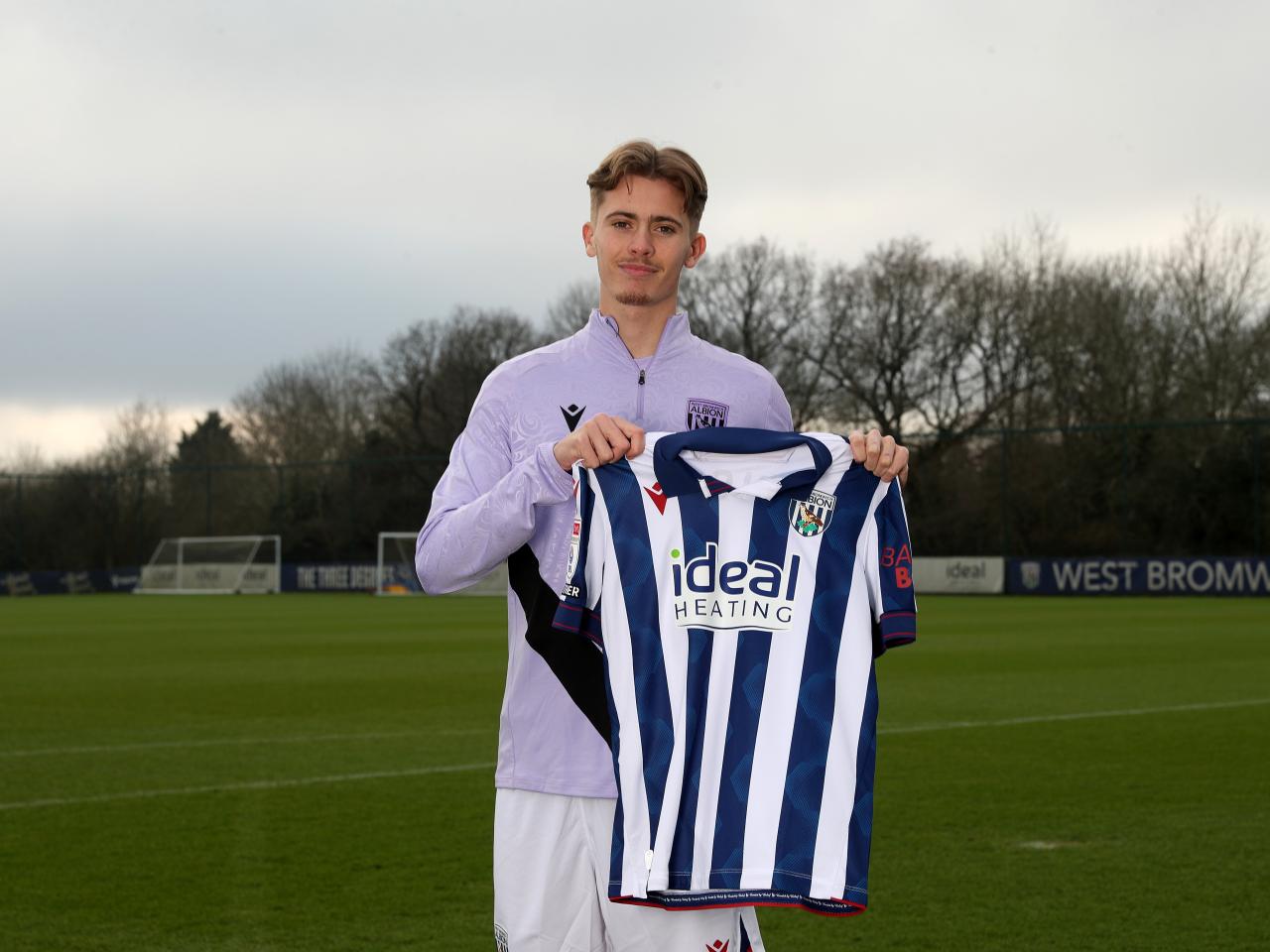 Isaac Price holding up a WBA home shirt 