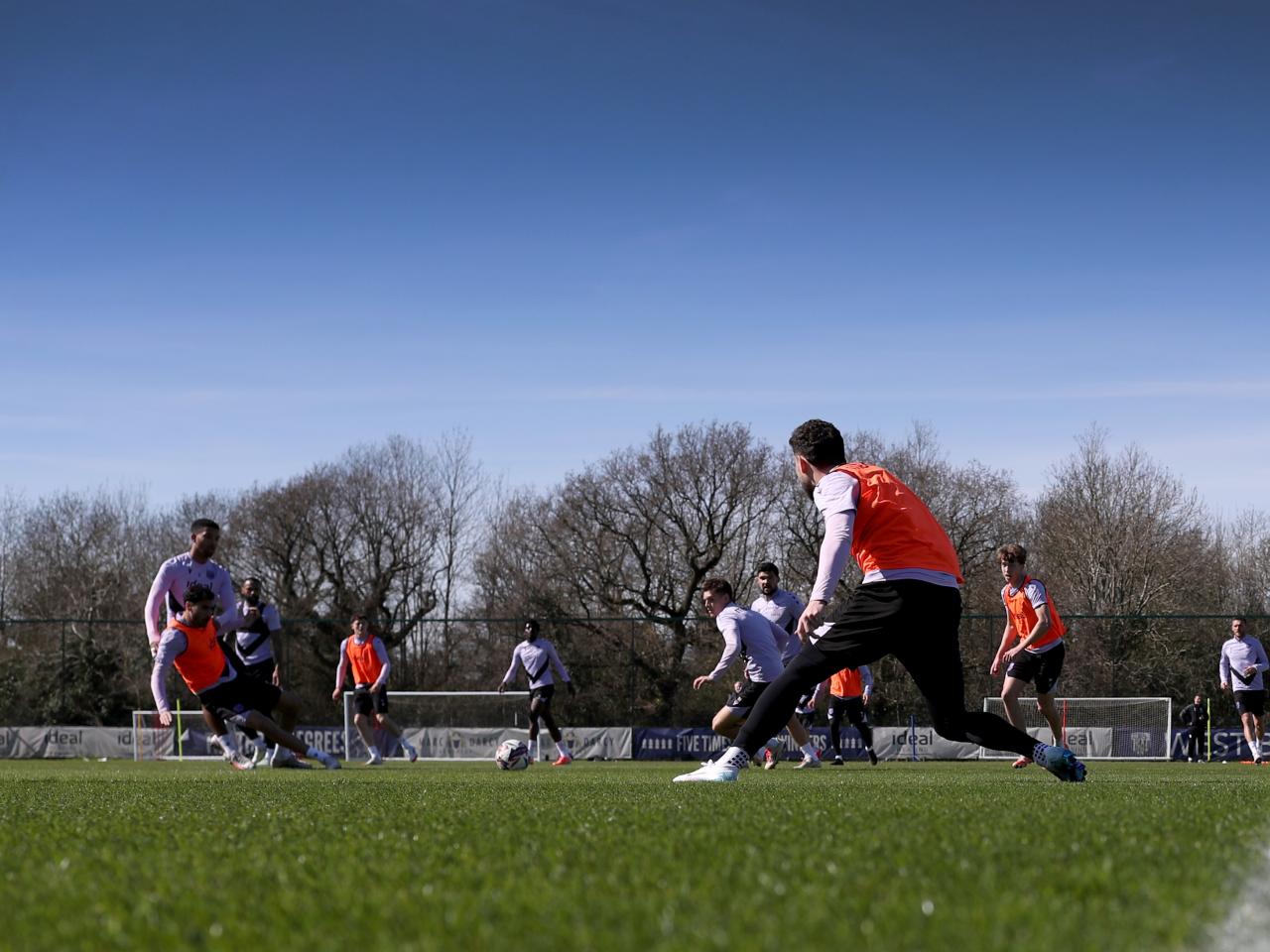 A general view of training in the sunlight with several players in shot