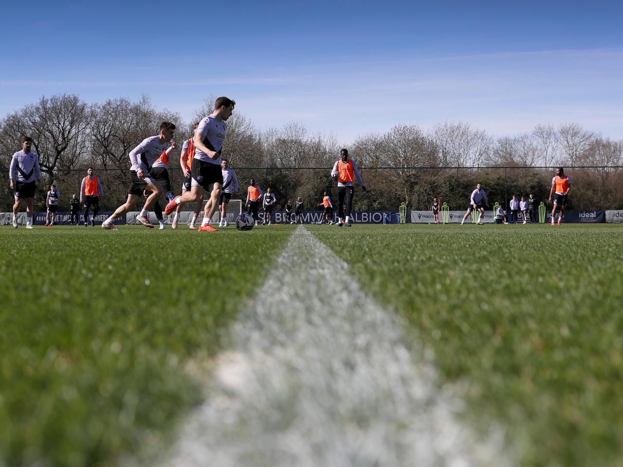 A general view of training with several players in shot and a white line on the pitch 