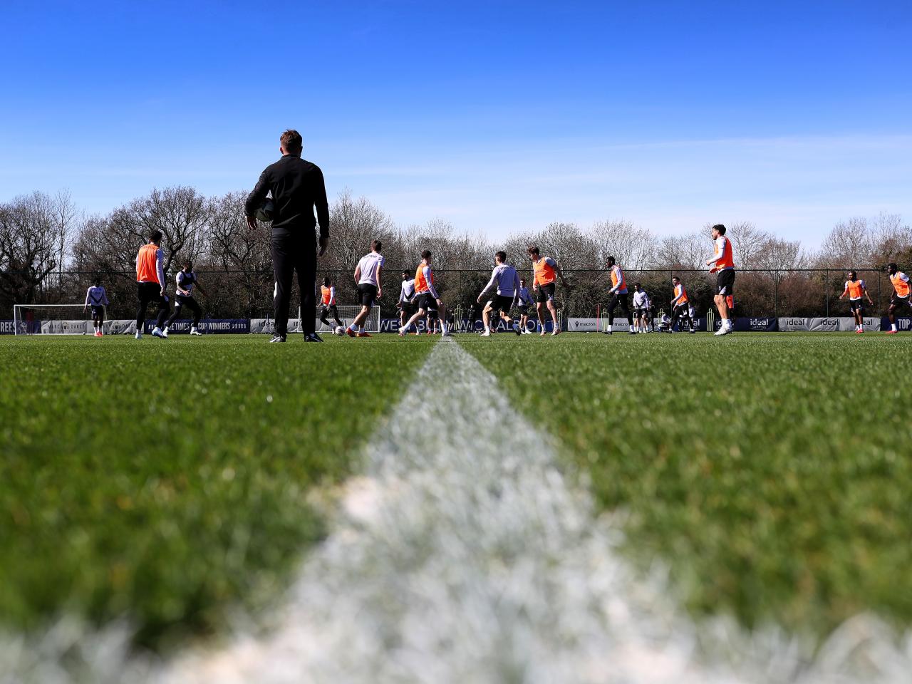 A general view of training with several players in shot and a white line on the pitch 