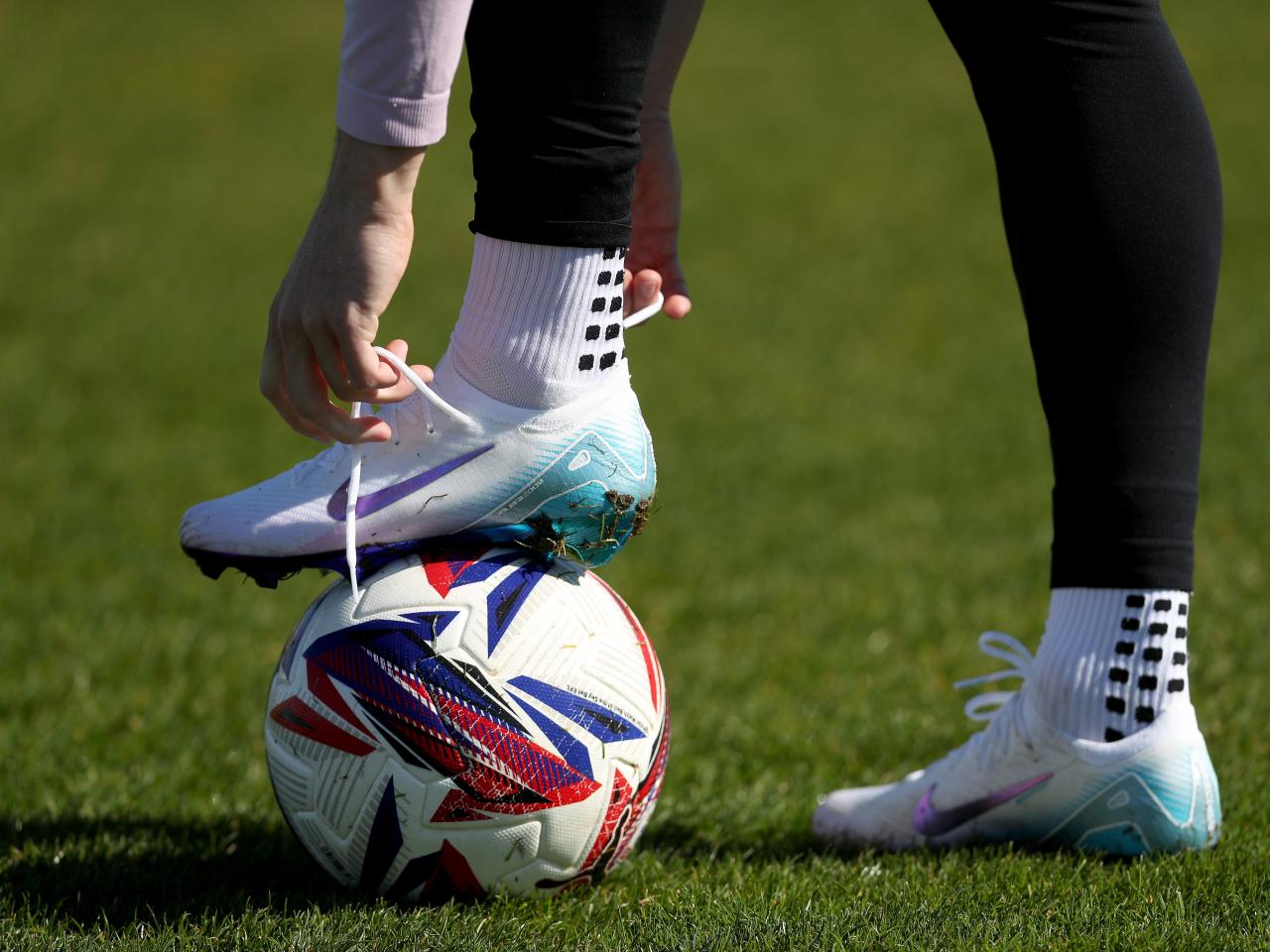 A WBA player tying up laces with his boot on a ball