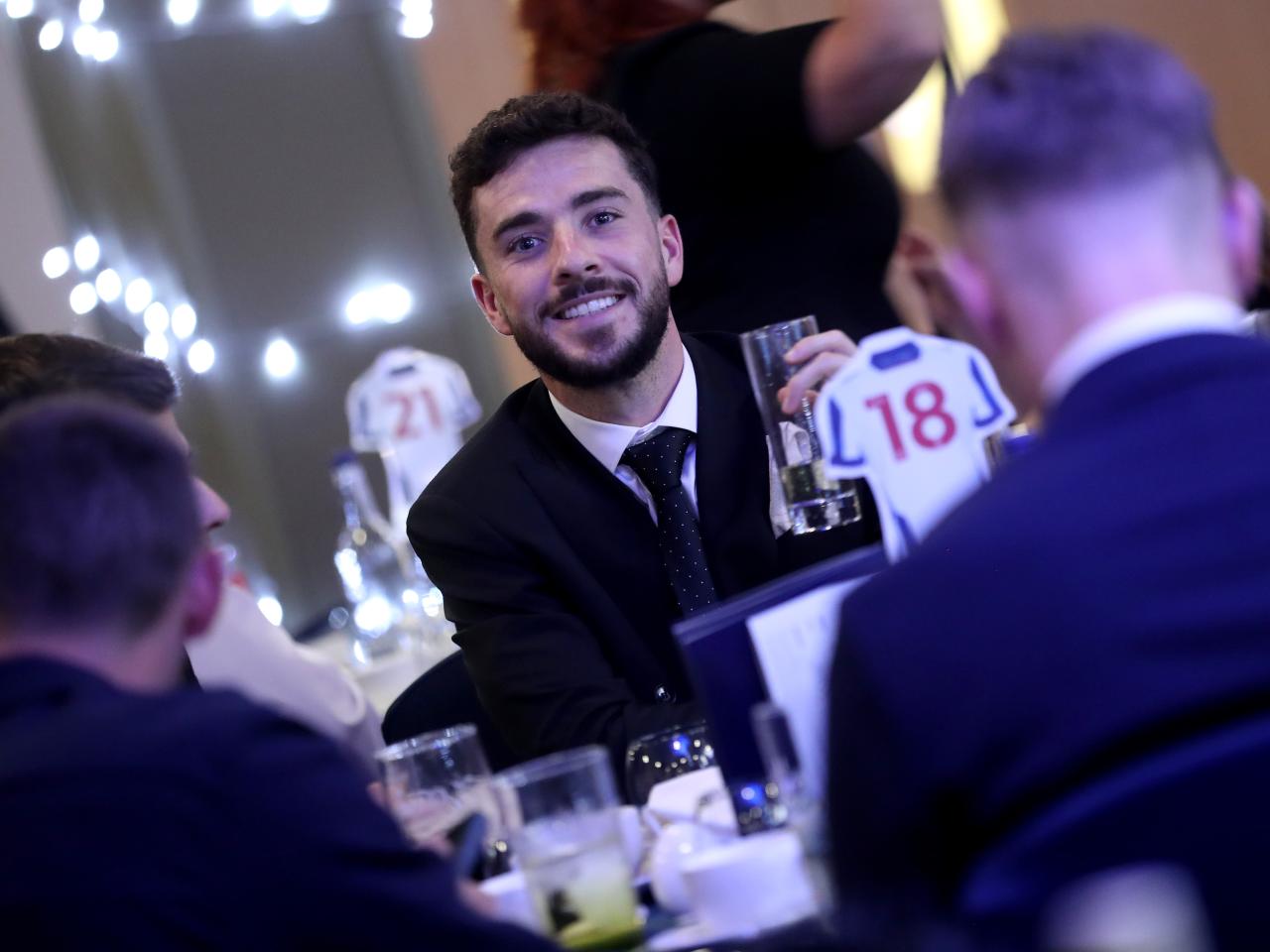 Mikey Johnston smiling at the camera while sat at a table at the end of season awards dinner