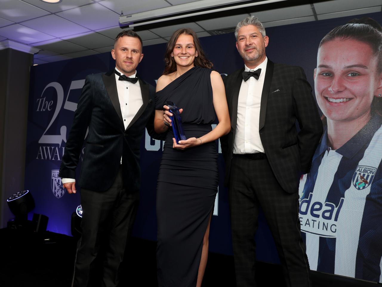 Izzy Green poses for a photo with an Albion Women member of staff and a sponsor on stage at the end of season awards dinner