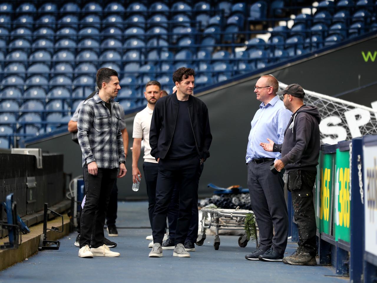 Ryan Mason stood on the side of the pitch at The Hawthorns talking to Andrew Nestor, Mark Miles and a groundsman