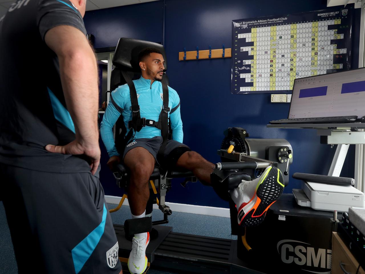 Karlan Grant sat in a gym seat carrying out a leg exercise 