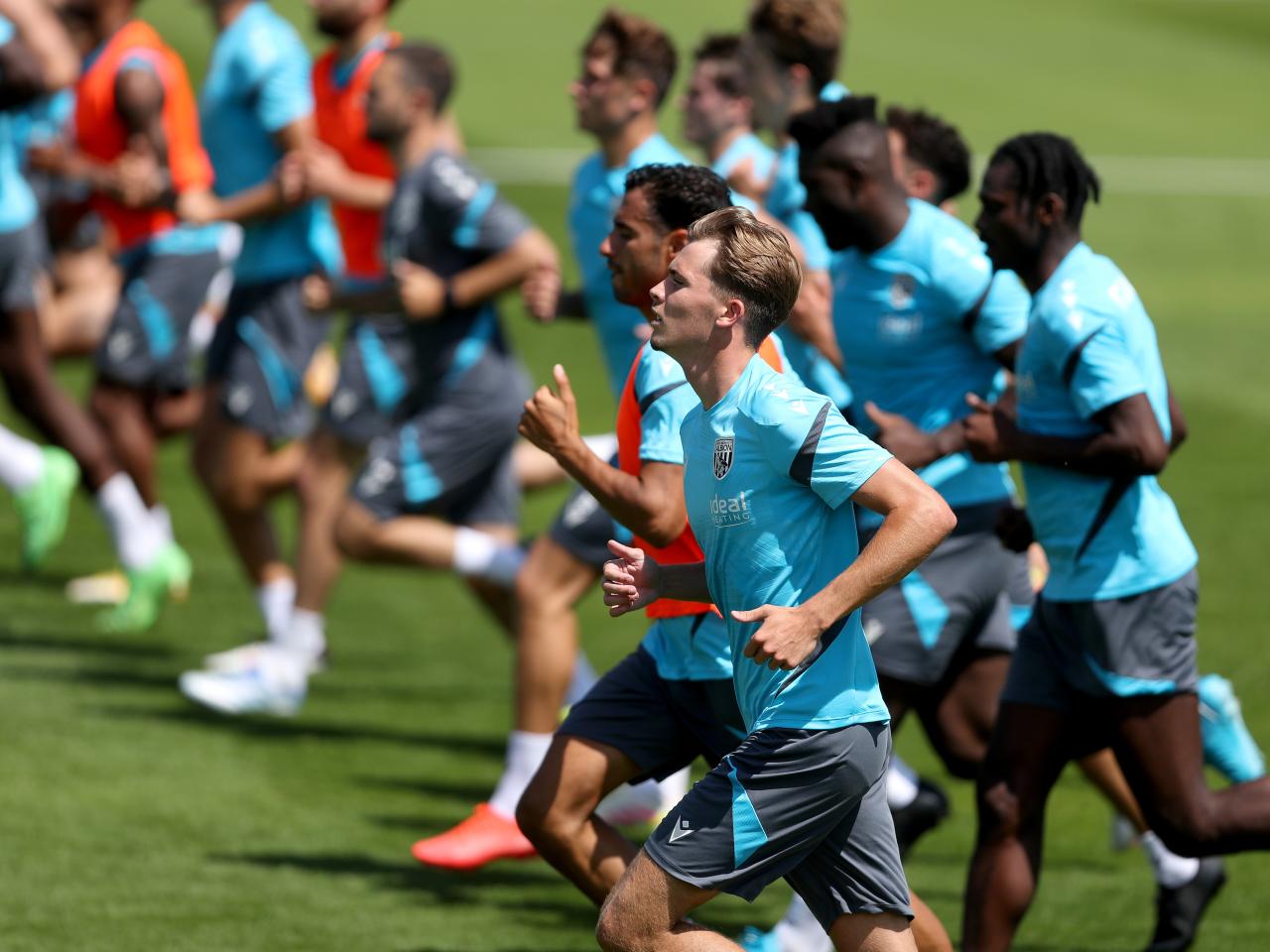 the first-team squad in a line running forward during a training session