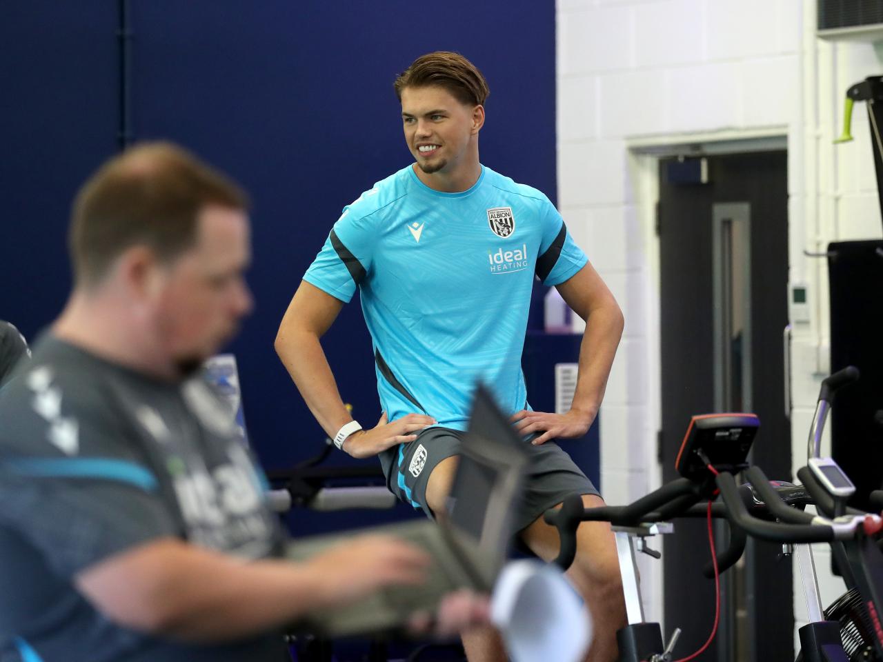 Josh Griffiths sat on an exercise bike in the gym smiling 