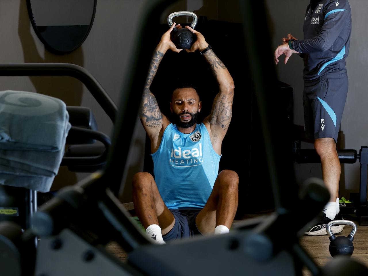 Kyle Bartley sat in the gym with a kettlebell weight above his head