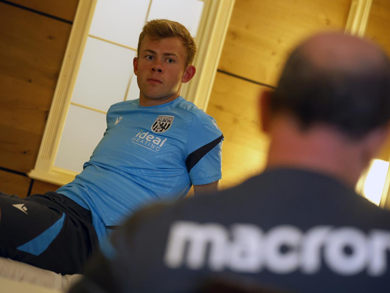 Aune Heggebø talking to a member of staff while sat on a medical bed