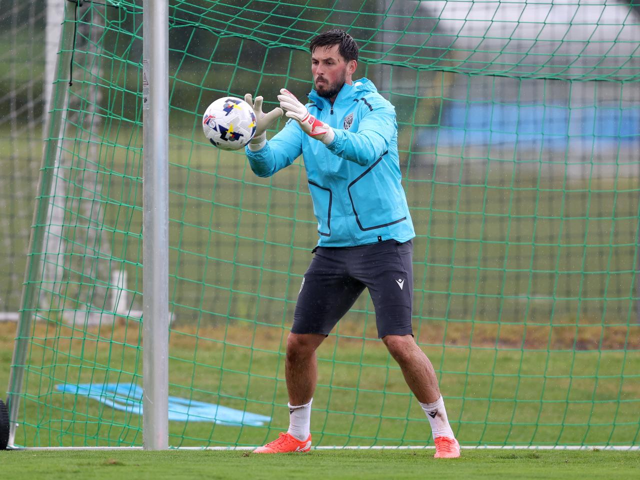 Joe Wildsmith saving a shot with his hands during a training session in the rain