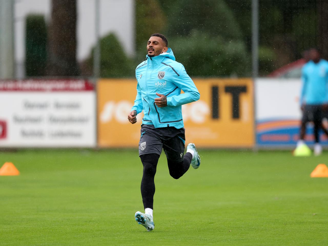 Karlan Grant running forward during a training session in the rain