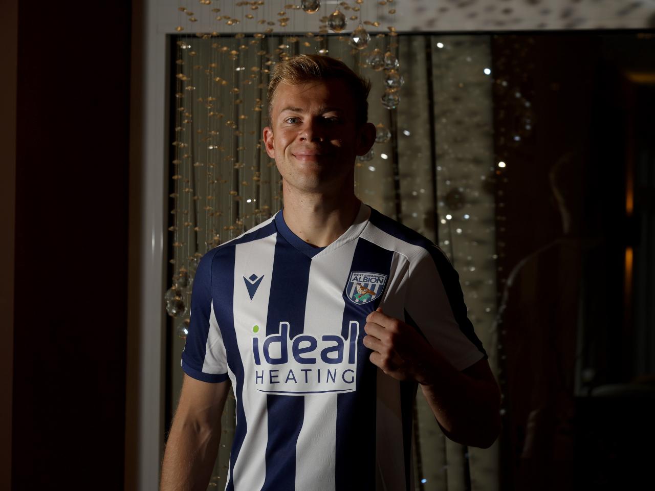 Aune Heggebø smiling at the camera while in a WBA shirt pulling on the badge