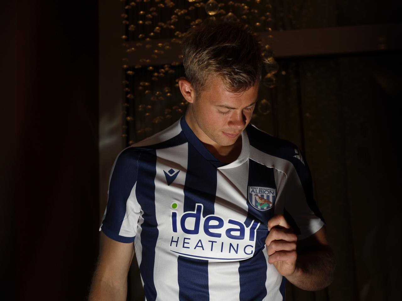 Aune Heggebø pulling the badge and looking at it while wearing a WBA shirt