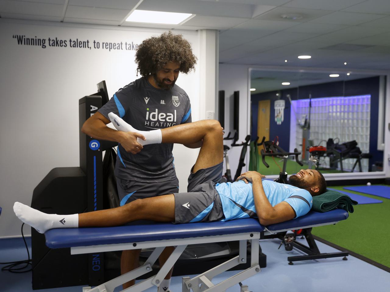 George Campbell laying on a medical bed stretching with a WBA physio 