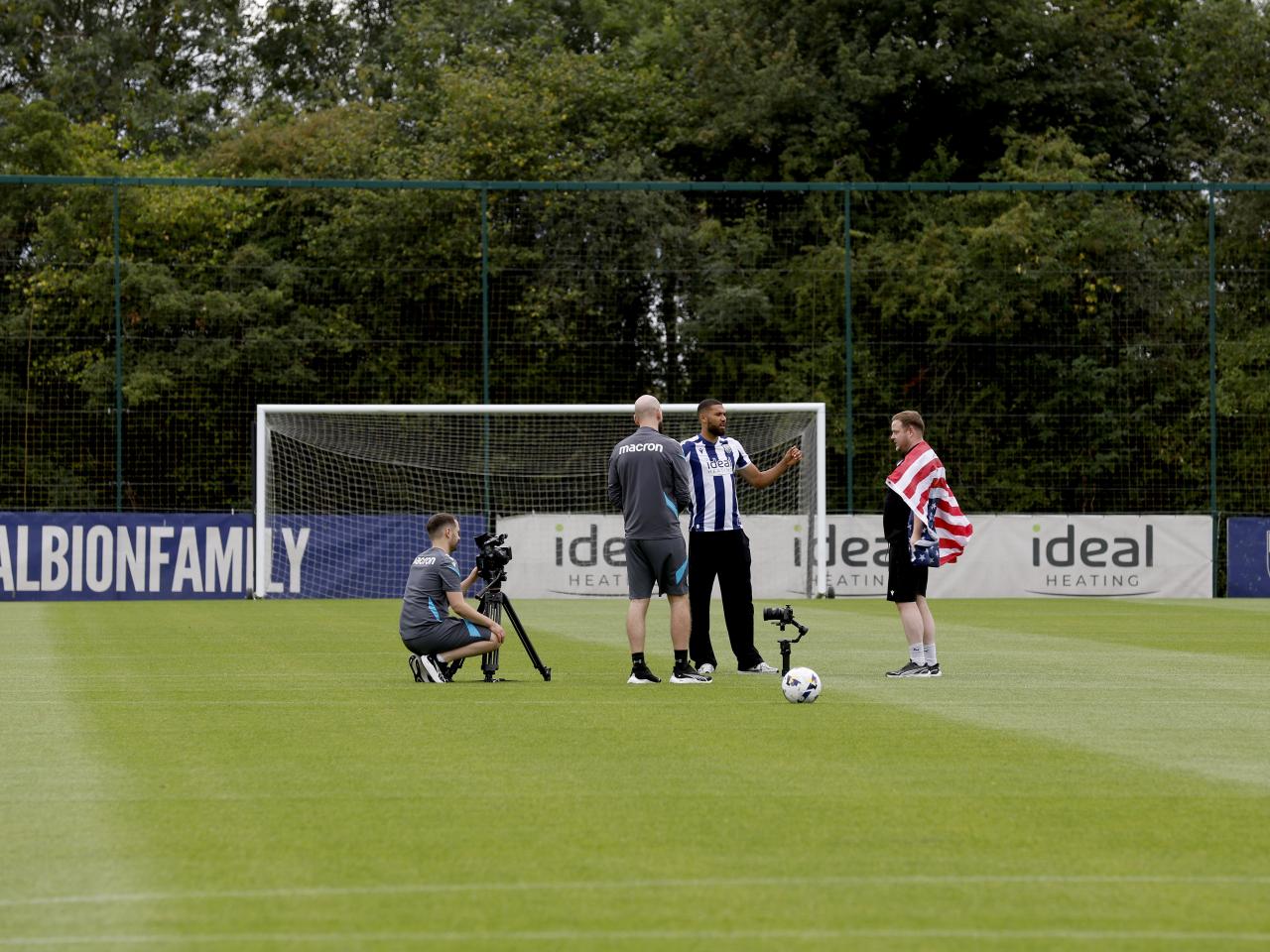 George Campbell is surrounded by WBA media staff in the middle of a training pitch 