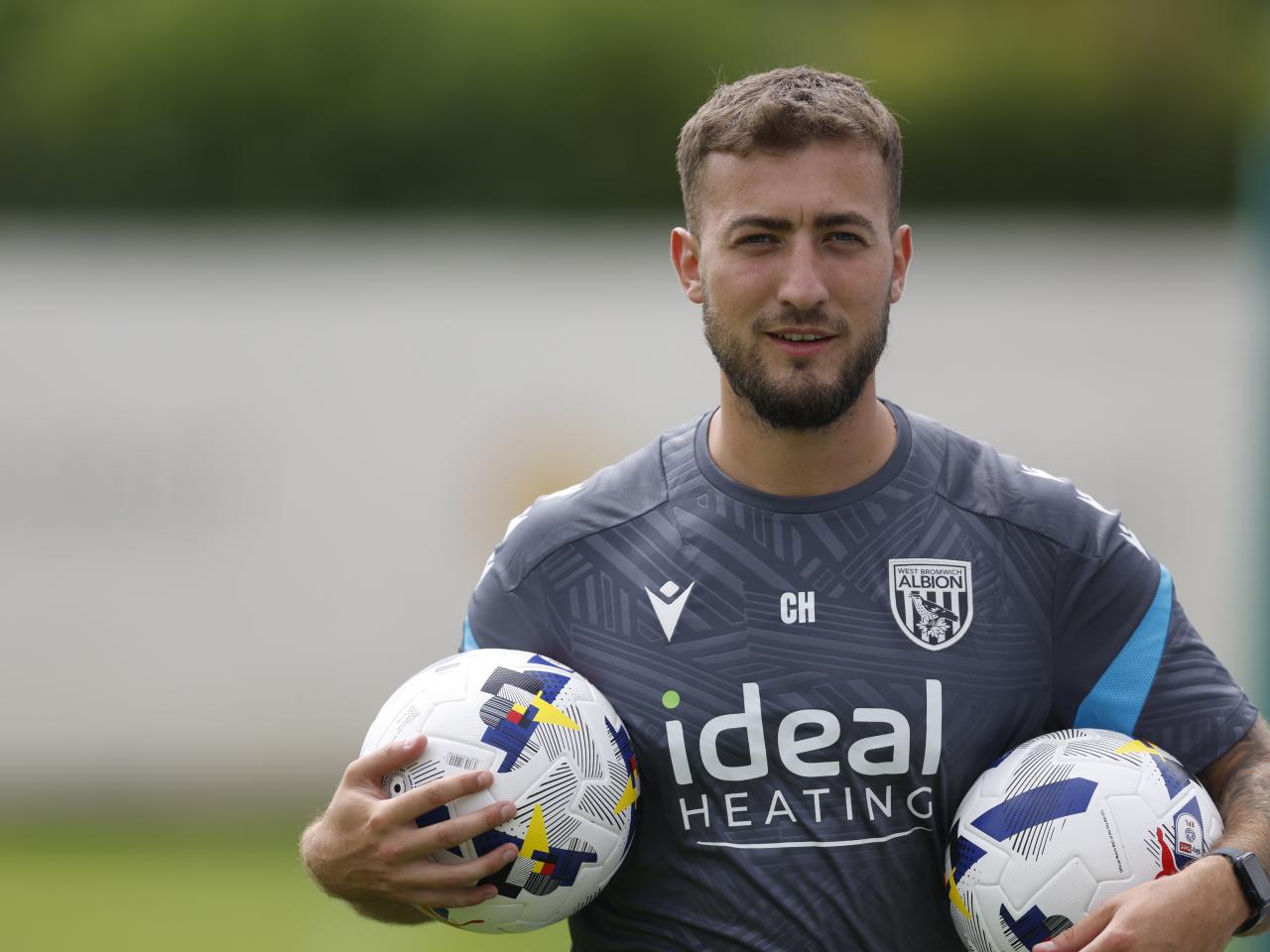 Albion kit man Curtis Holmes carrying two balls on the training pitch