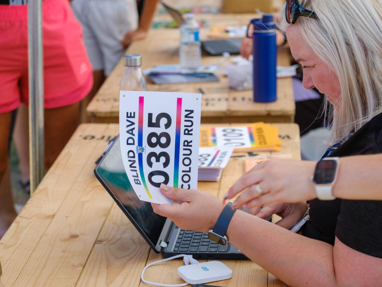 Foundation staff member handing on runners number at registration desk