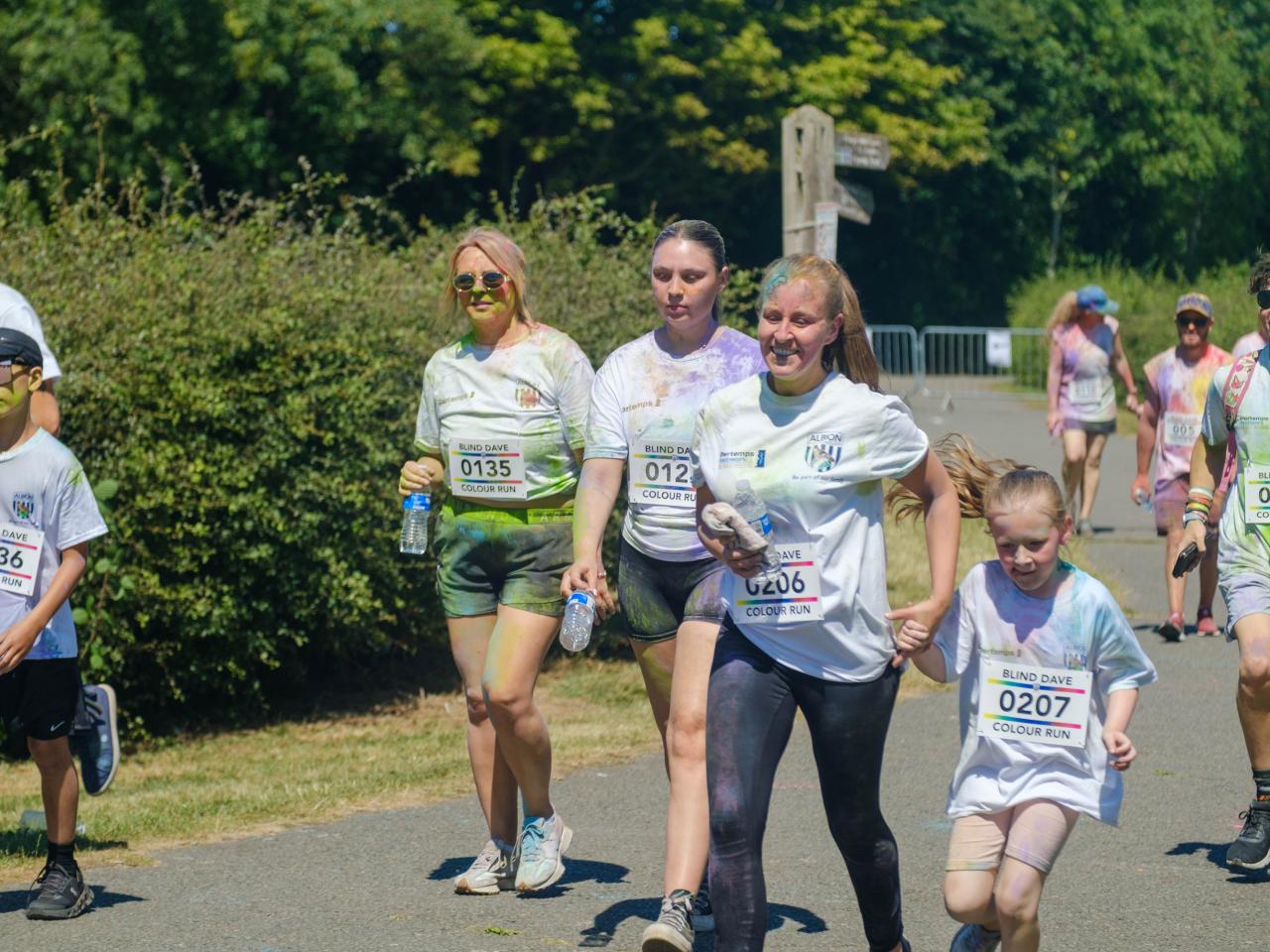 More runners smiling, heading towards the finish line.