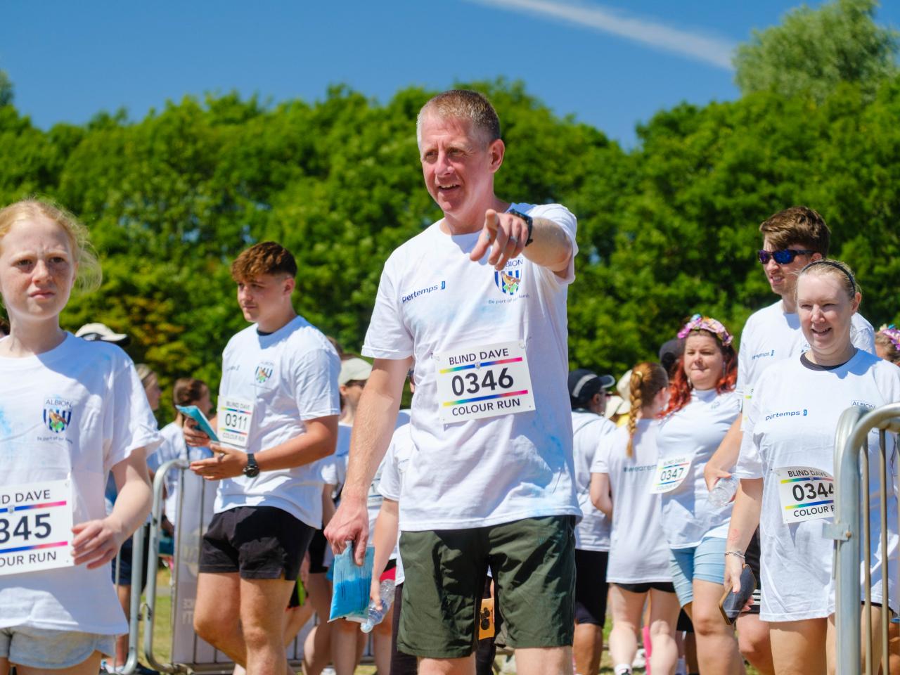 Runners walking in to the warm up area, one runner, pointing at the camera.