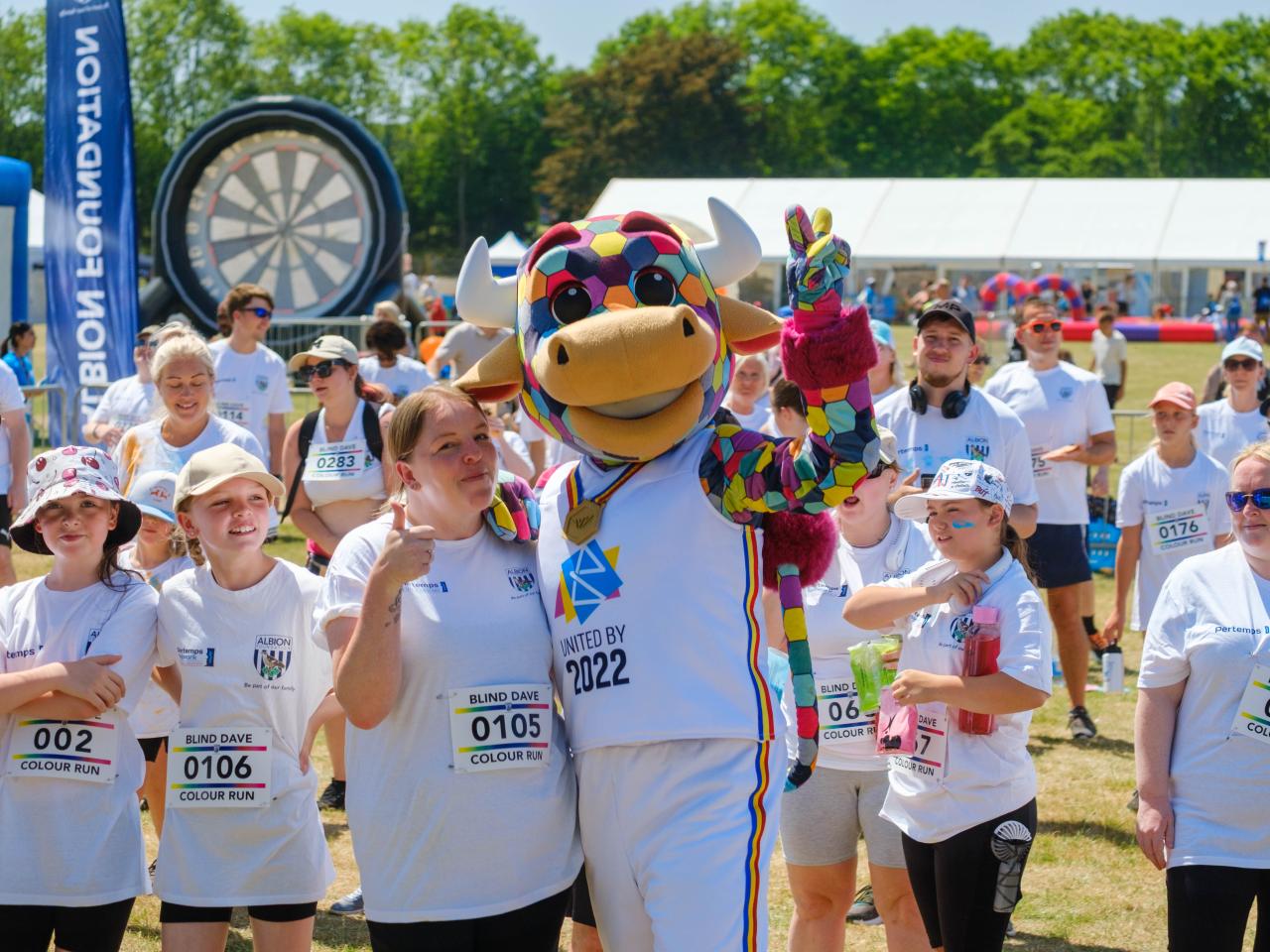 Perry the Bull with arm around a participant and thumb up, as the group pose for a photo.
