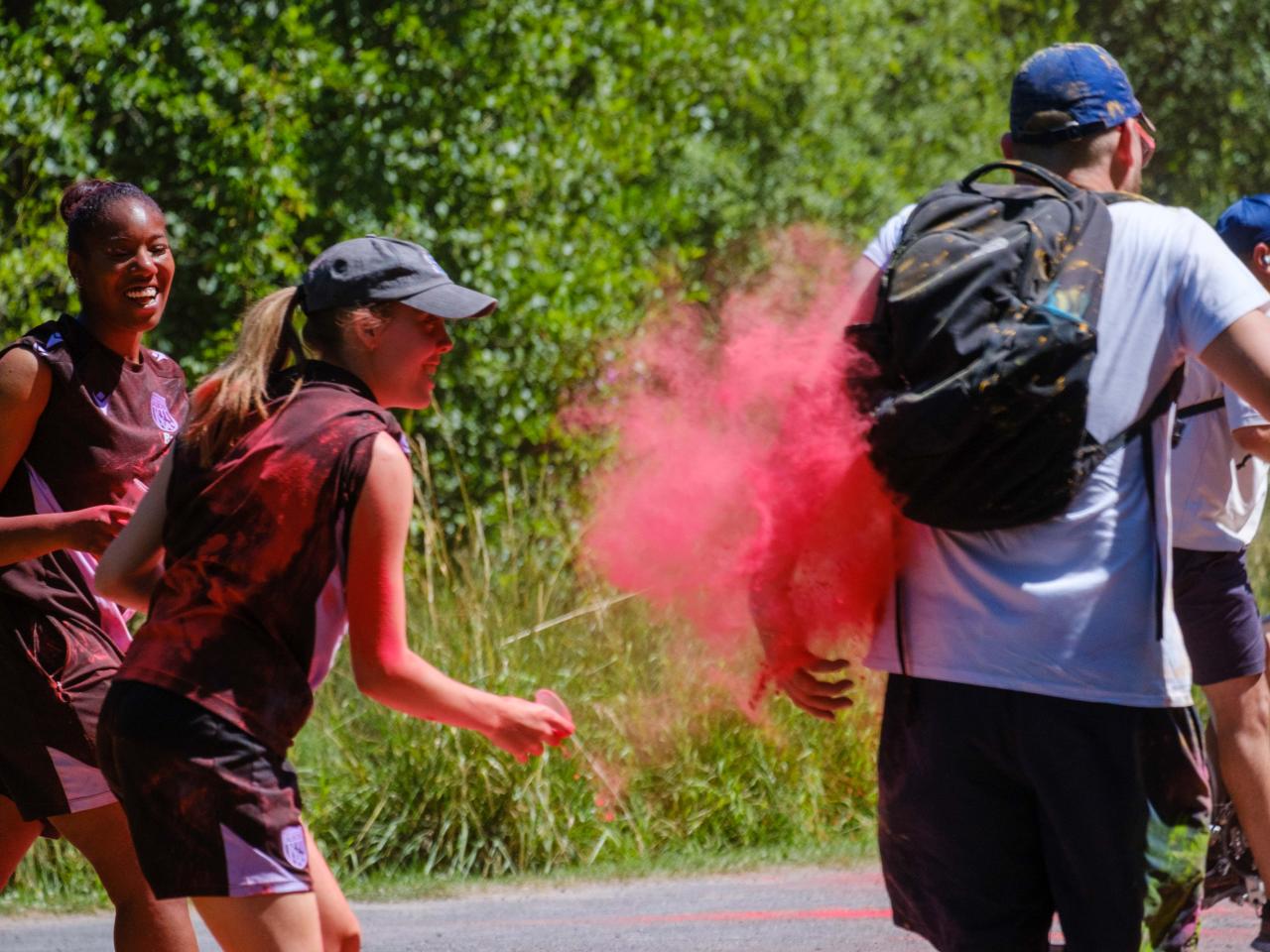 Two Foundation staff members aiming paint powder at a passing runner.