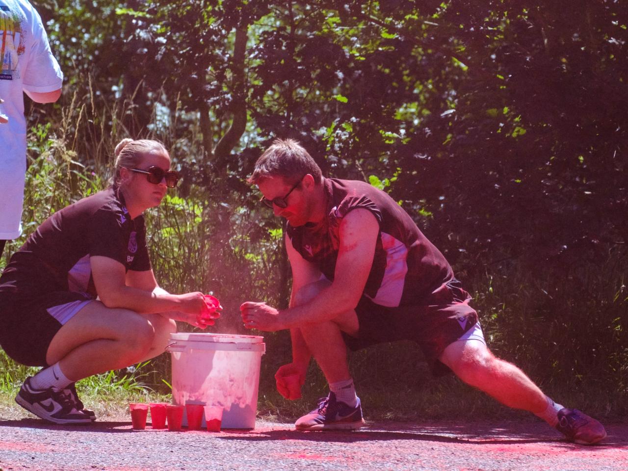 Close up of two Foundation staff members topping up their cups with paint powder.