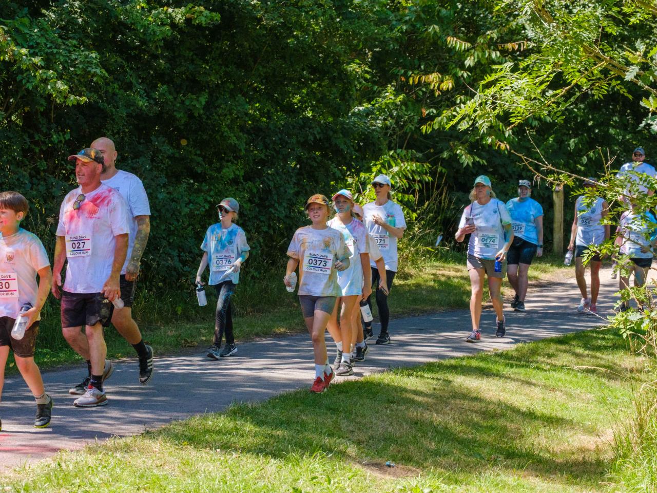 Participants running along shaded greenery.