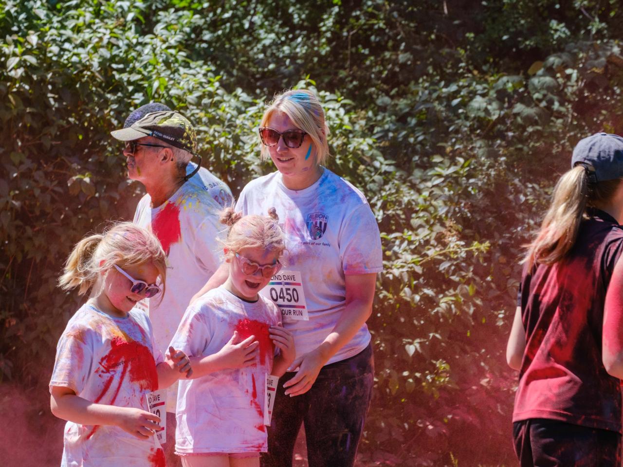 Runners passing colour station being douse with red powder.