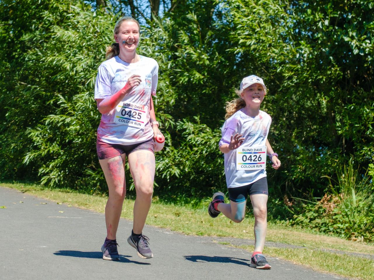 Mother and daughter, waving and smiling, running on the path.