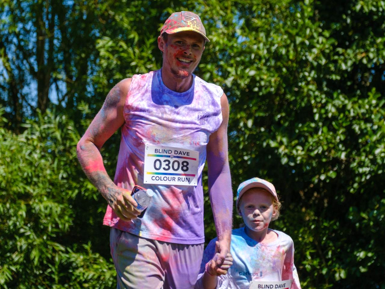Father holding child hand, covered in multiple tones of paint