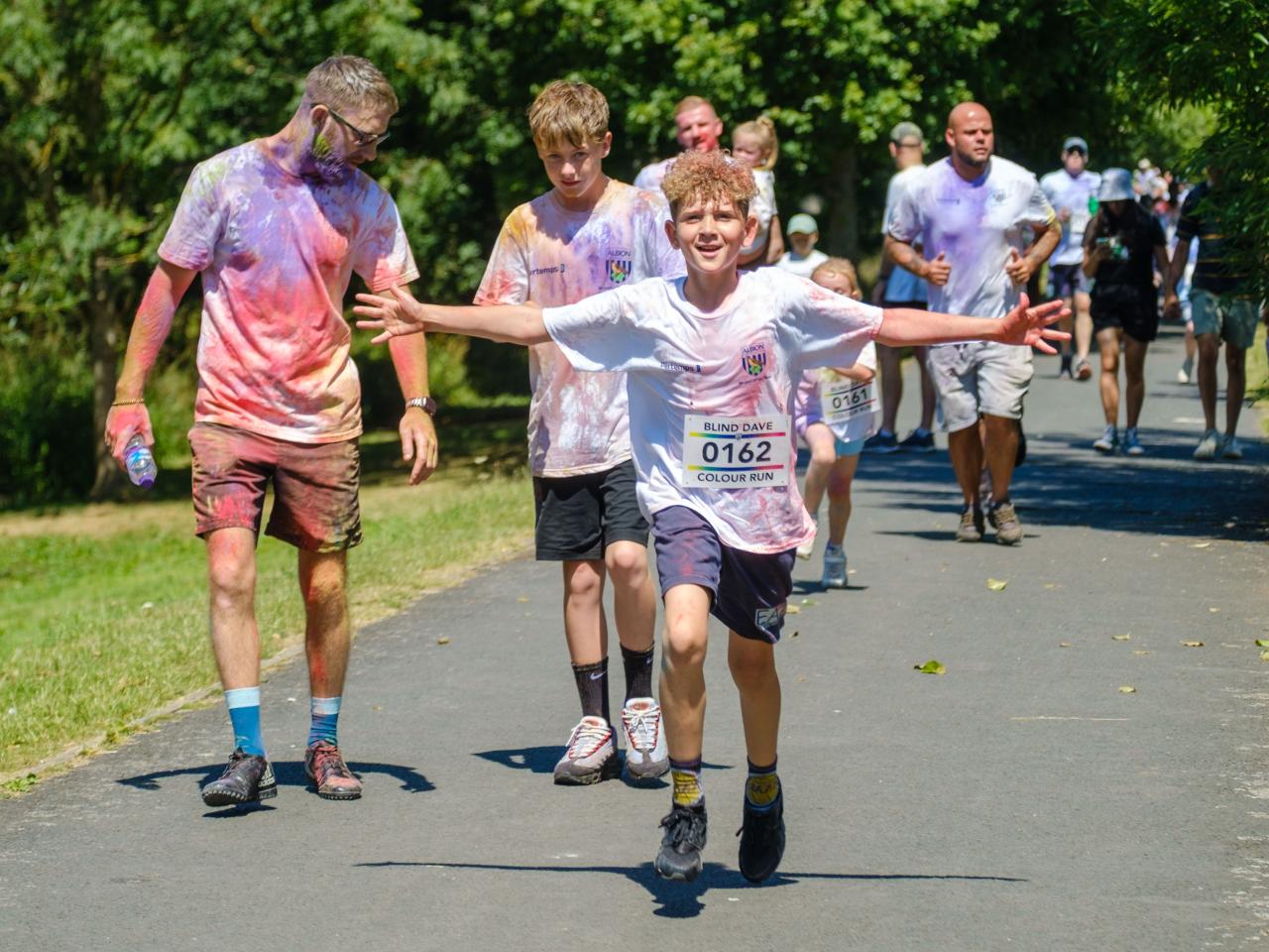 Young runner, with arms stretched out. Group of runners in the background.