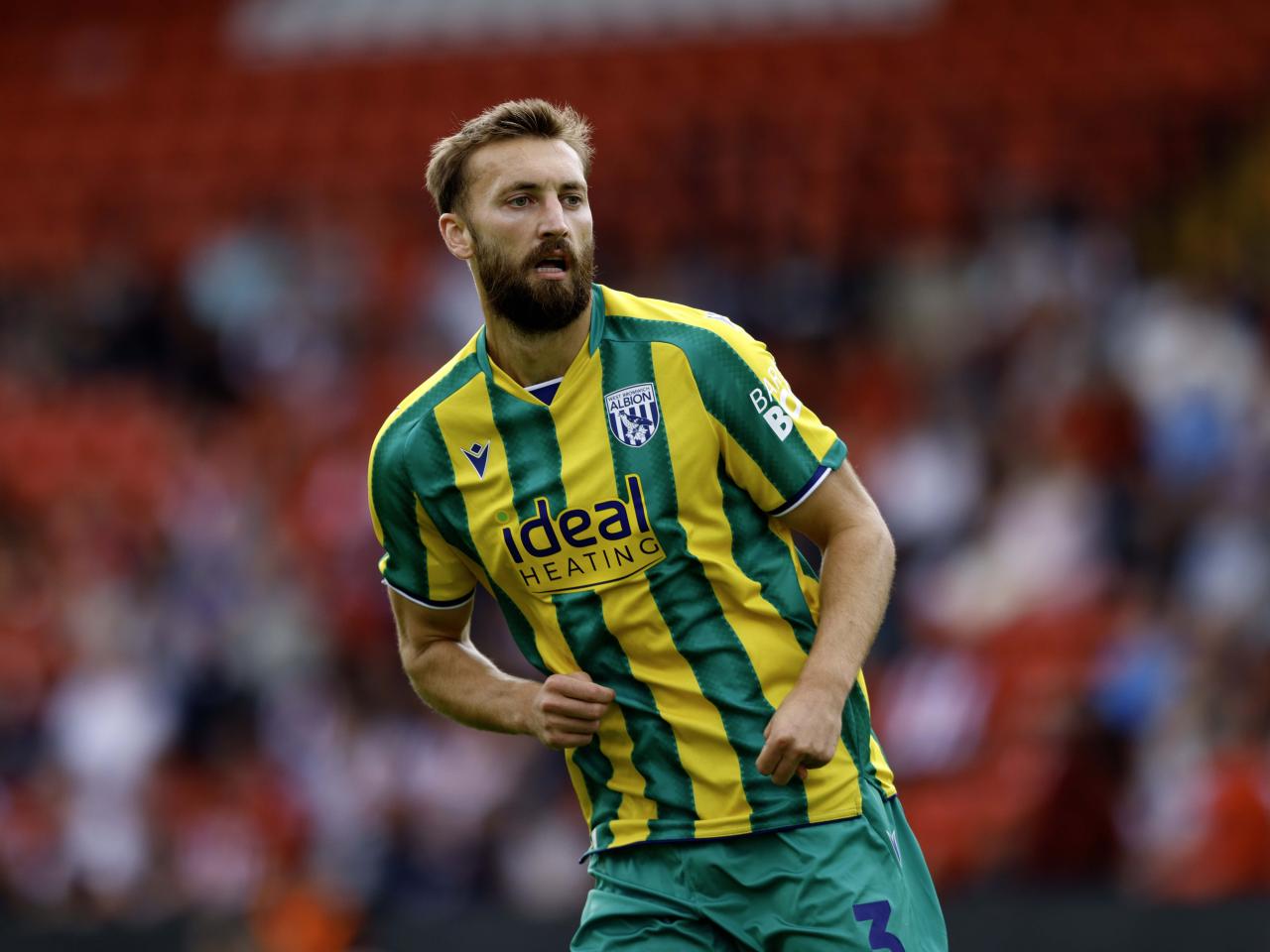 A photo of Nat Phillips in the 2025/26 green and yellow away kit