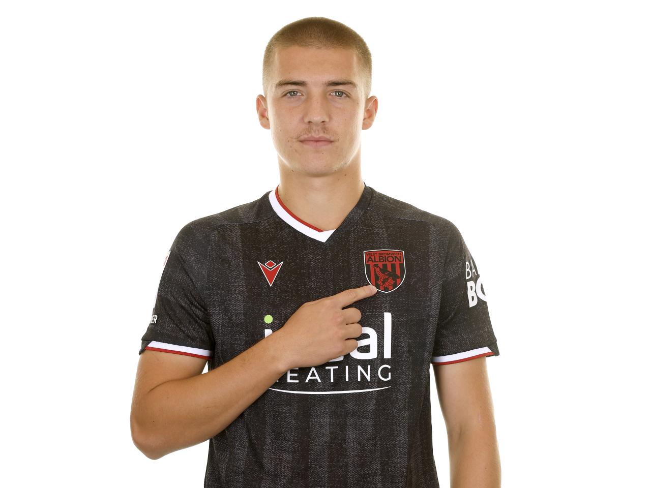 Alfie Gilchrist looking at the camera while stood in a black away shirt