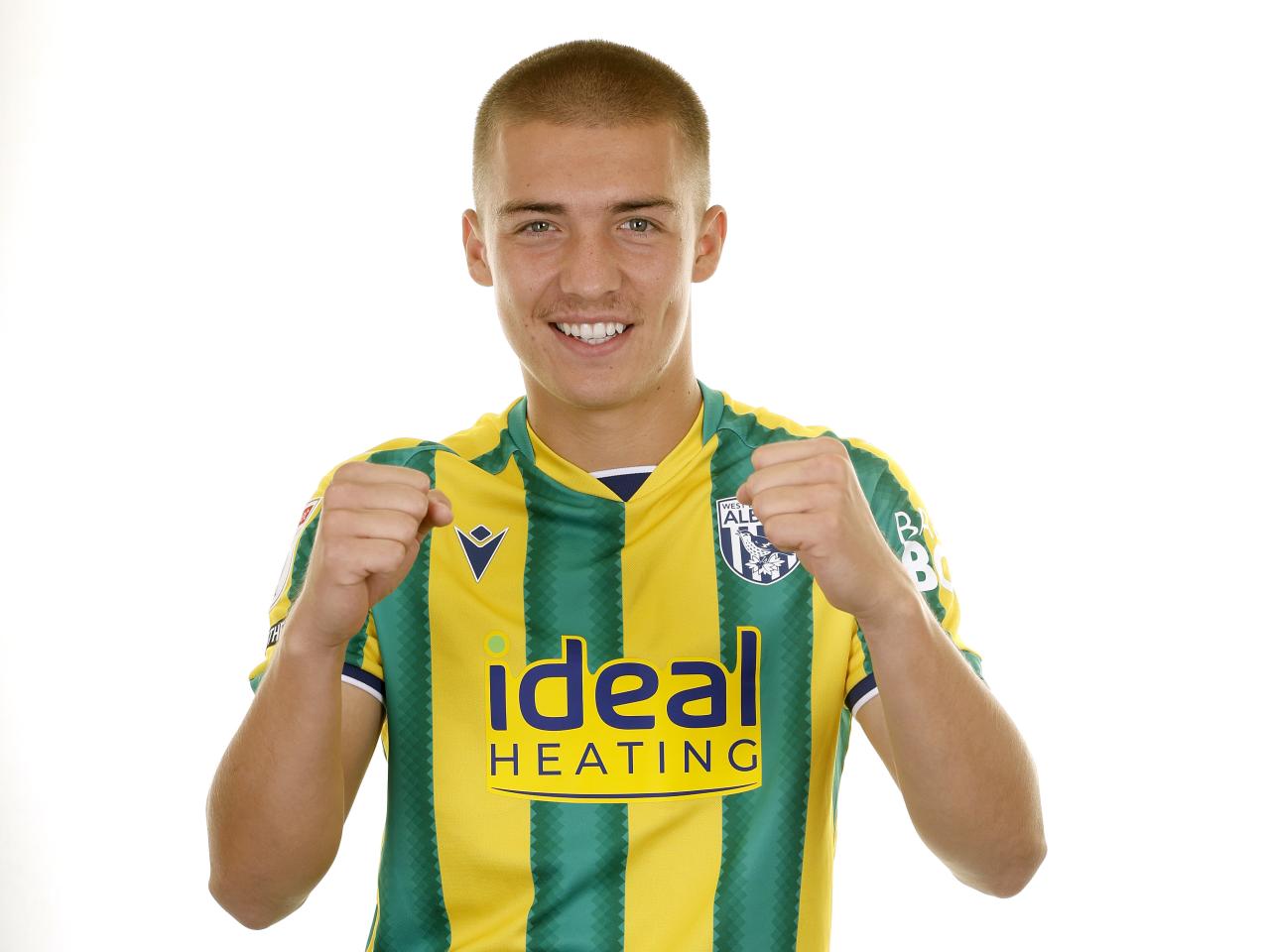 Alfie Gilchrist smiling at the camera while stood in a green and yellow shirt