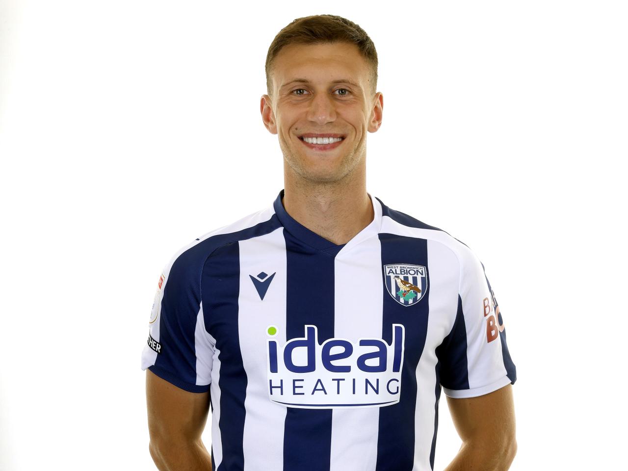 Krystian Bielik smiling at the camera in the home kit 