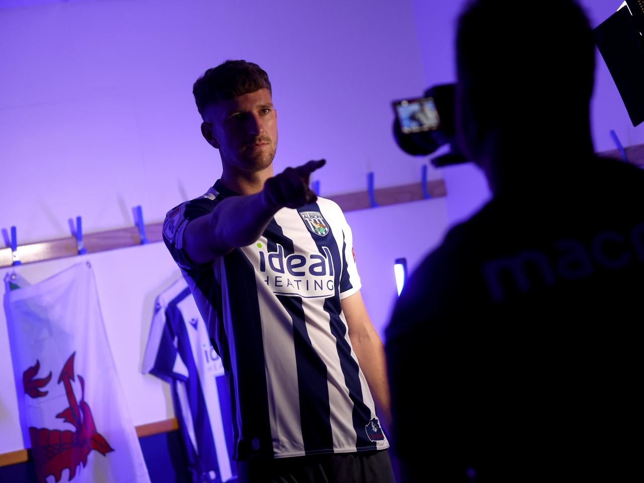 Chris Mepham pointing at a camera while being stood in a home shirt 