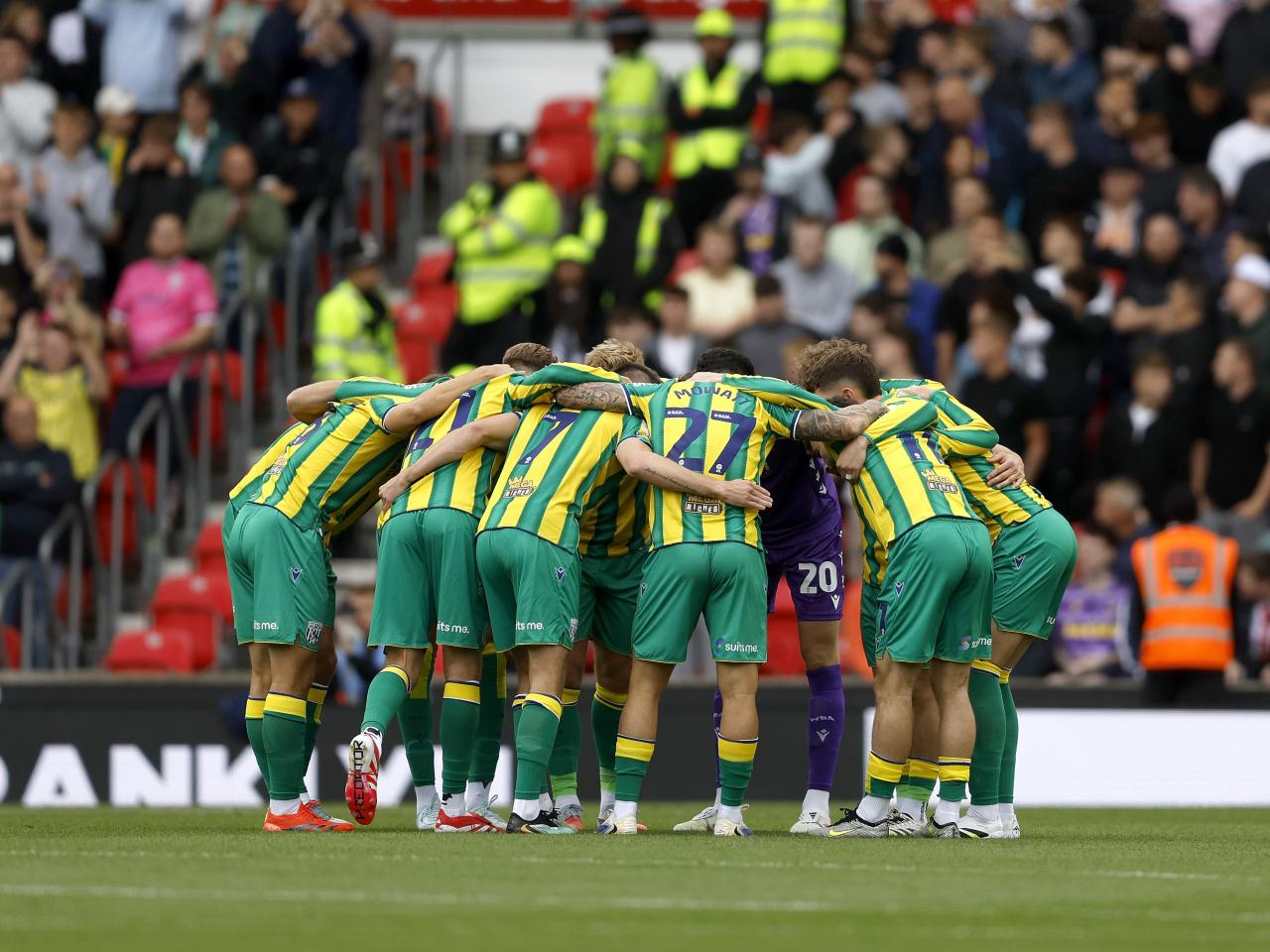 Albion players in the green and yellow away kit in a pre-match huddle before the Stoke game