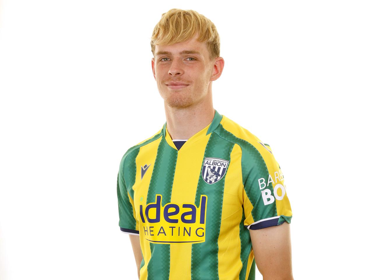Toby Collyer smiling at the camera while wearing the green and yellow away shirt