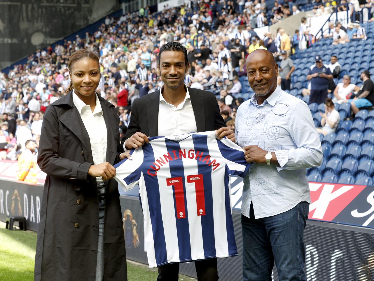 Jayda Regis, Sergio Cunningham and Brendon Batson holding up a WBA shirt with 'Cunningham 11' on the back
