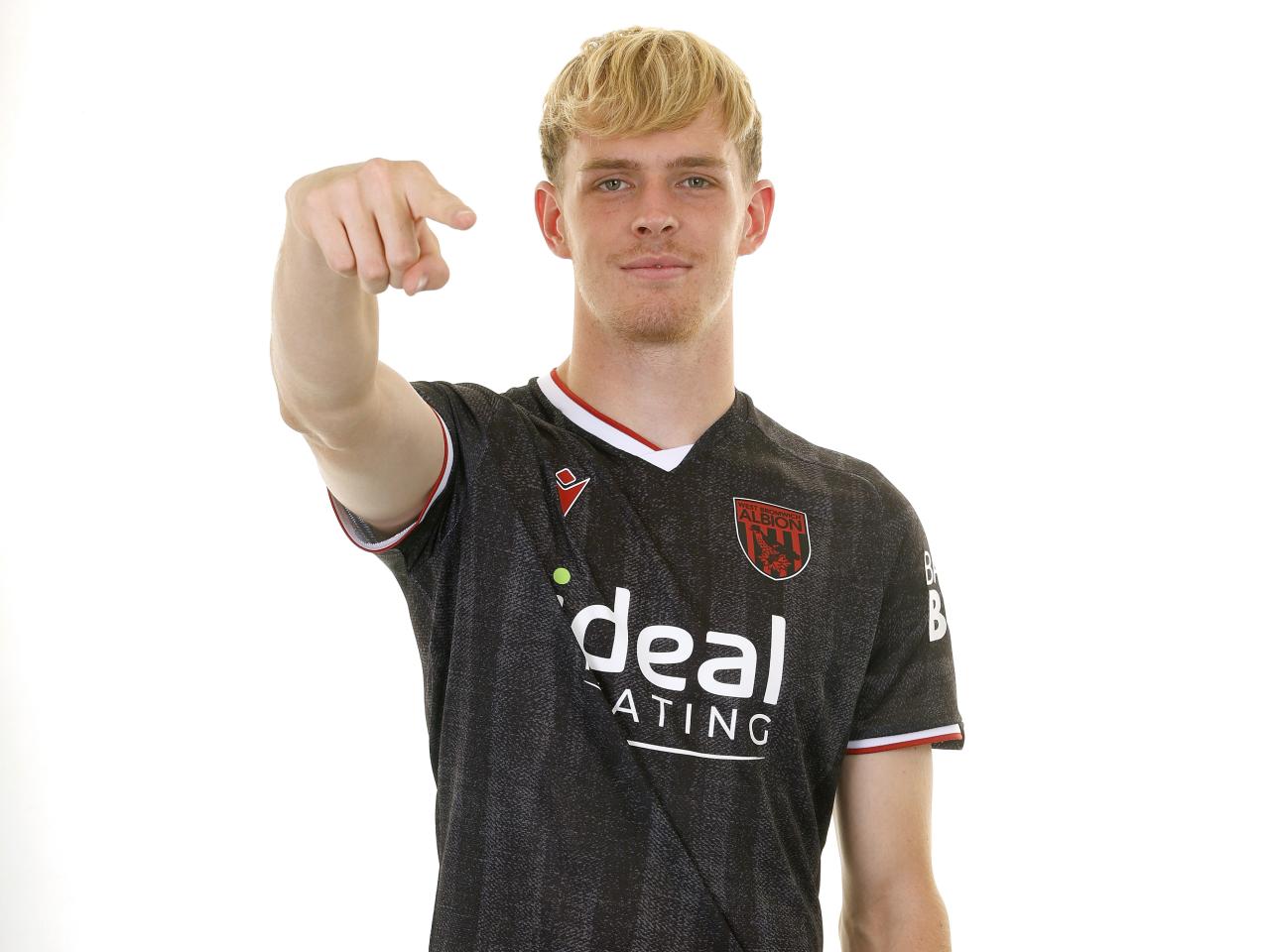 Toby Collyer smiling and pointing at the camera while wearing the black away kit 