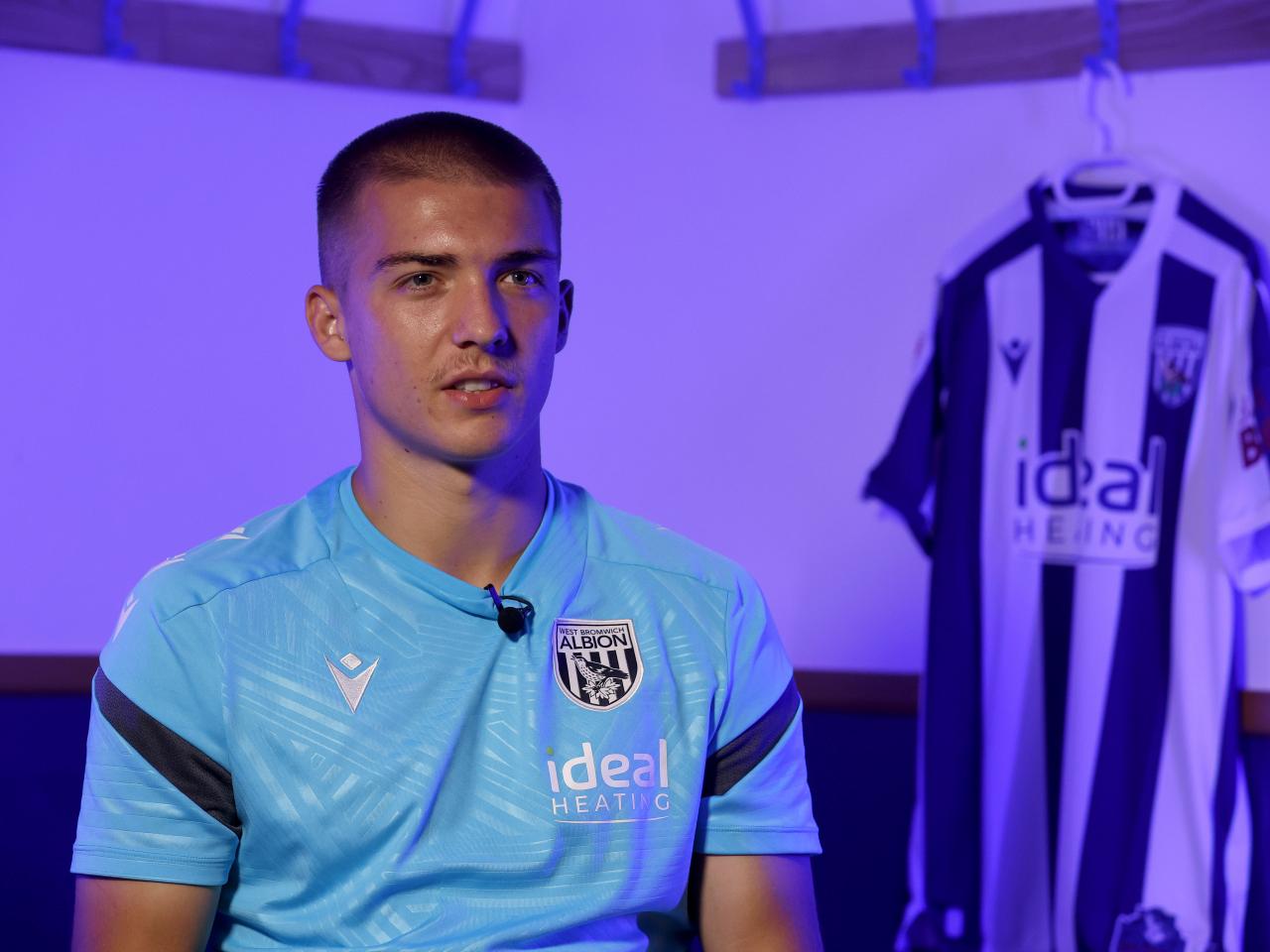 Alfie Gilchrist speaking to WBA TV with a WBA home shirt in the background hanging up