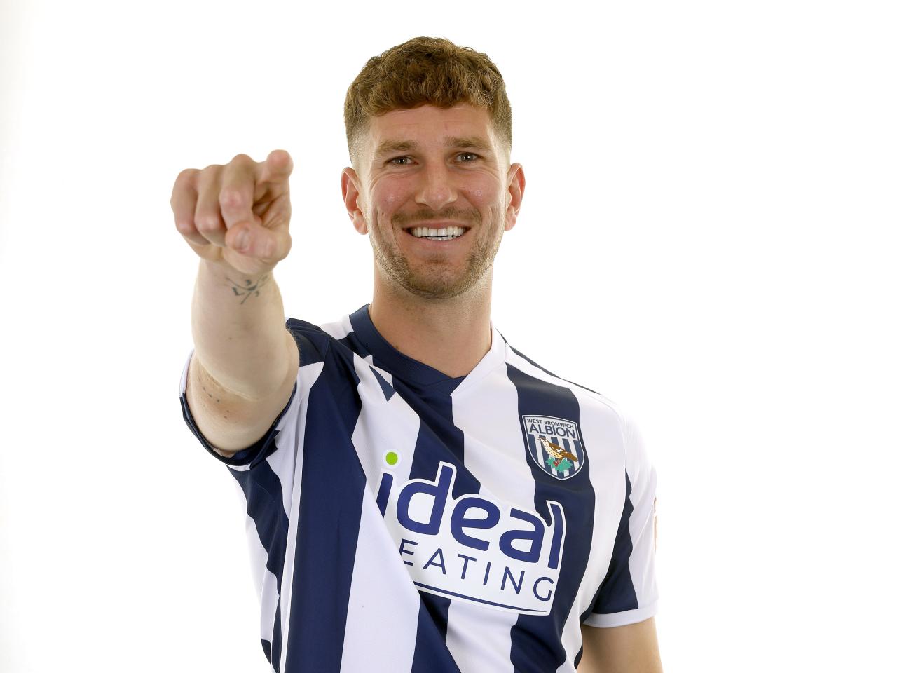 Chris Mepham in the home kit smiling and pointing at the camera 