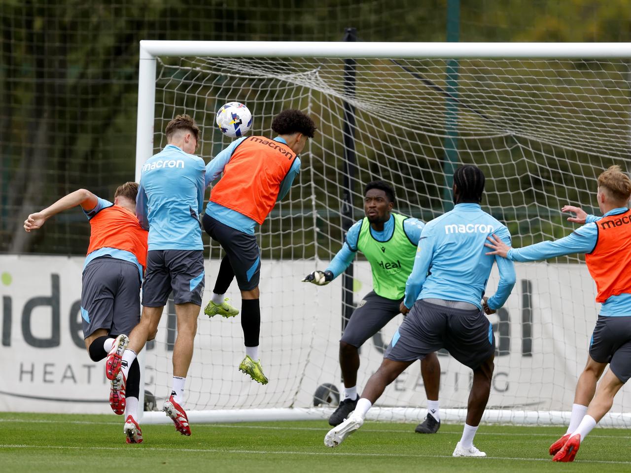 General training action with several players jumping to win the ball