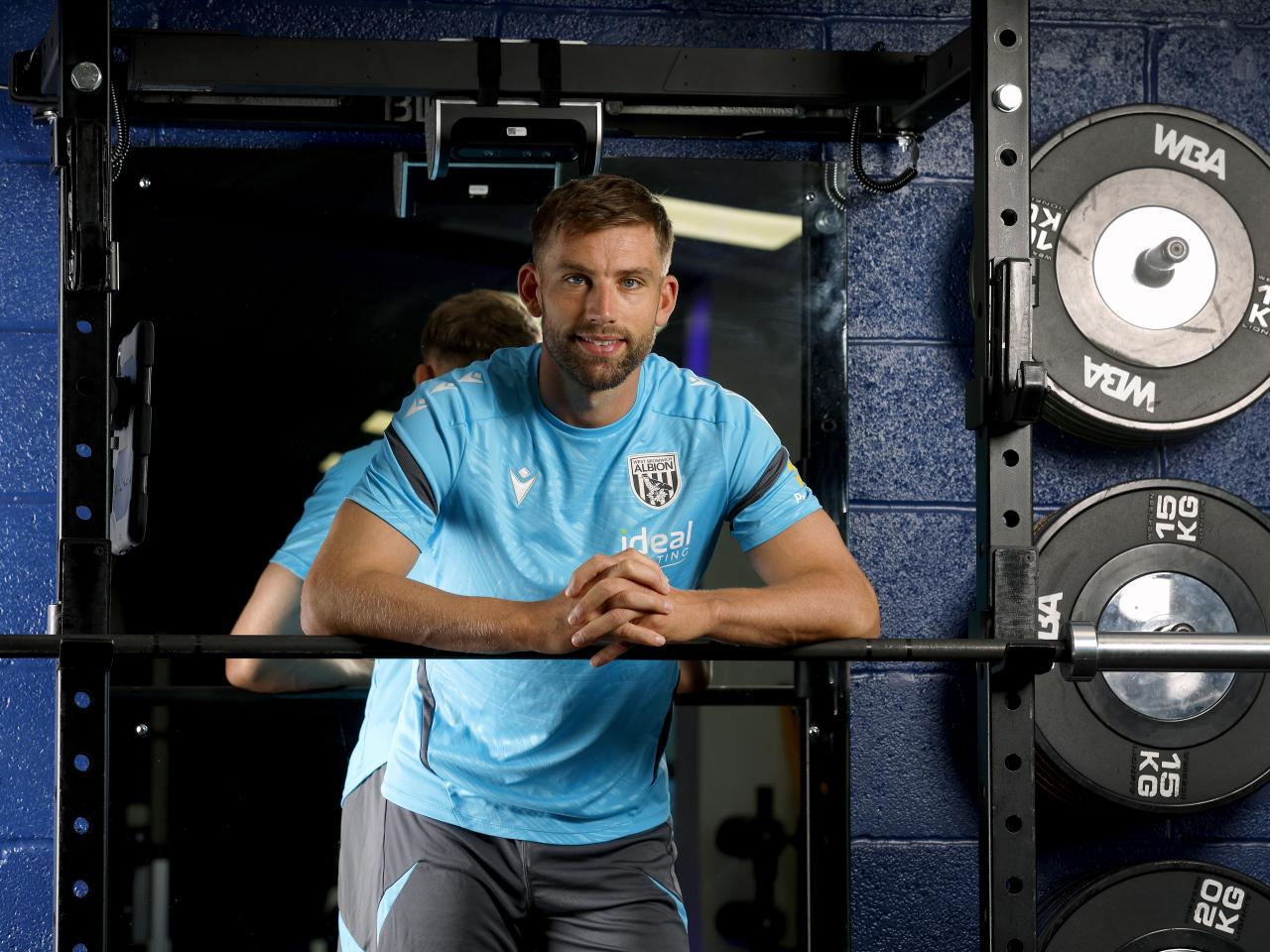 Charlie Taylor smiling at the camera while leaning on a bar in the gym
