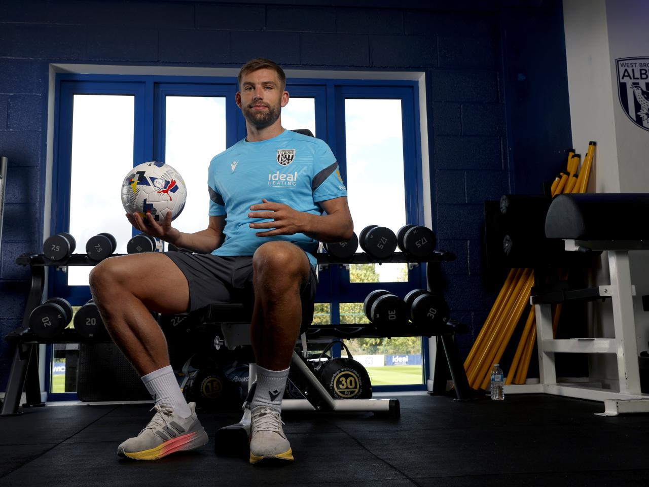 Charlie Taylor smiling at the camera while sat in the gym holding a ball