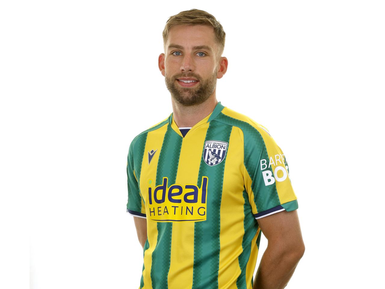 Charlie Taylor posing for a photo in the green and yellow away kit in front of a white background 