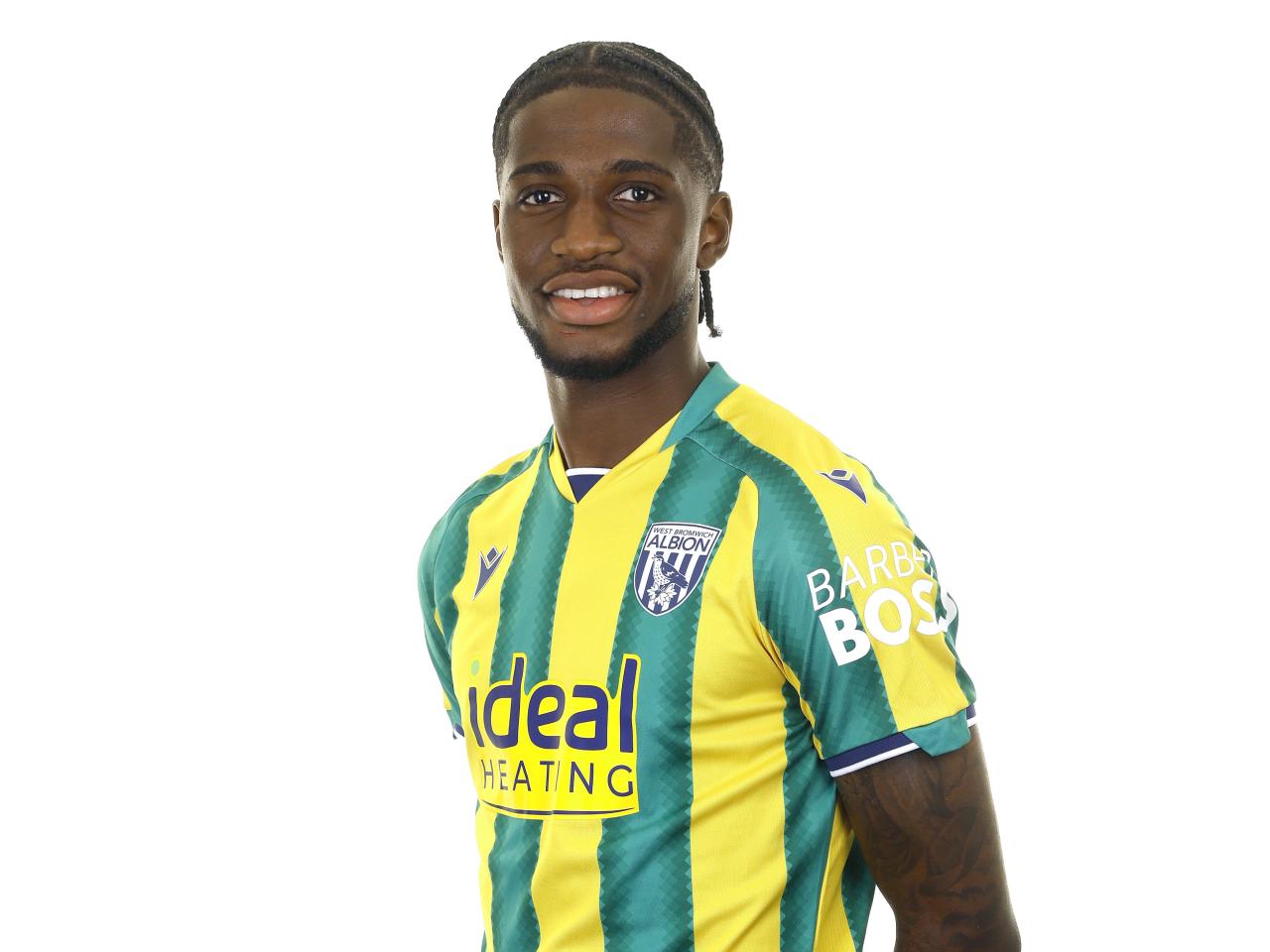 Samuel Iling-Junior posing for a photo in the green and yellow kit in front of a white background