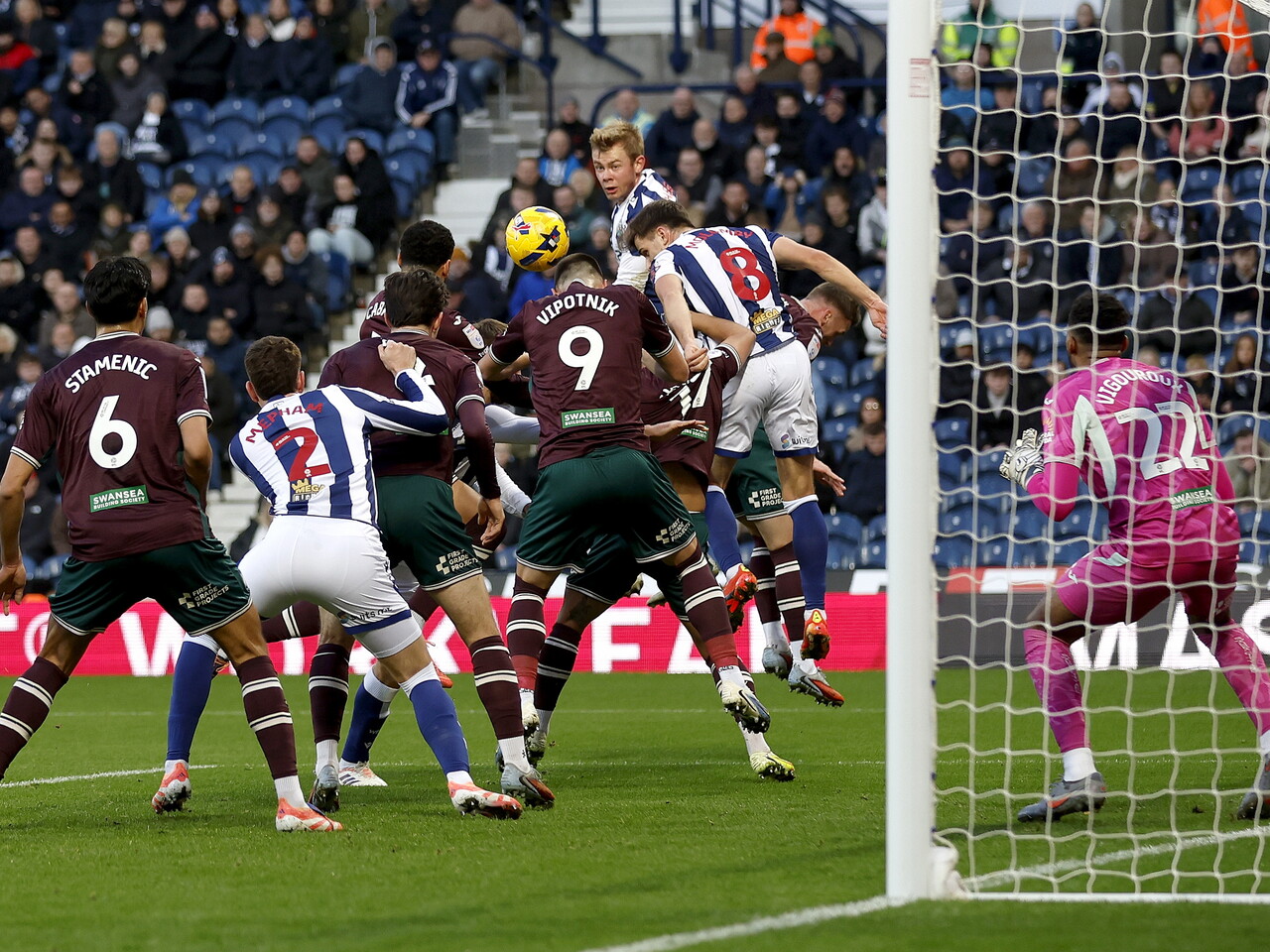Several players jumping to win a header in the penalty area during the game between WBA and Swansea