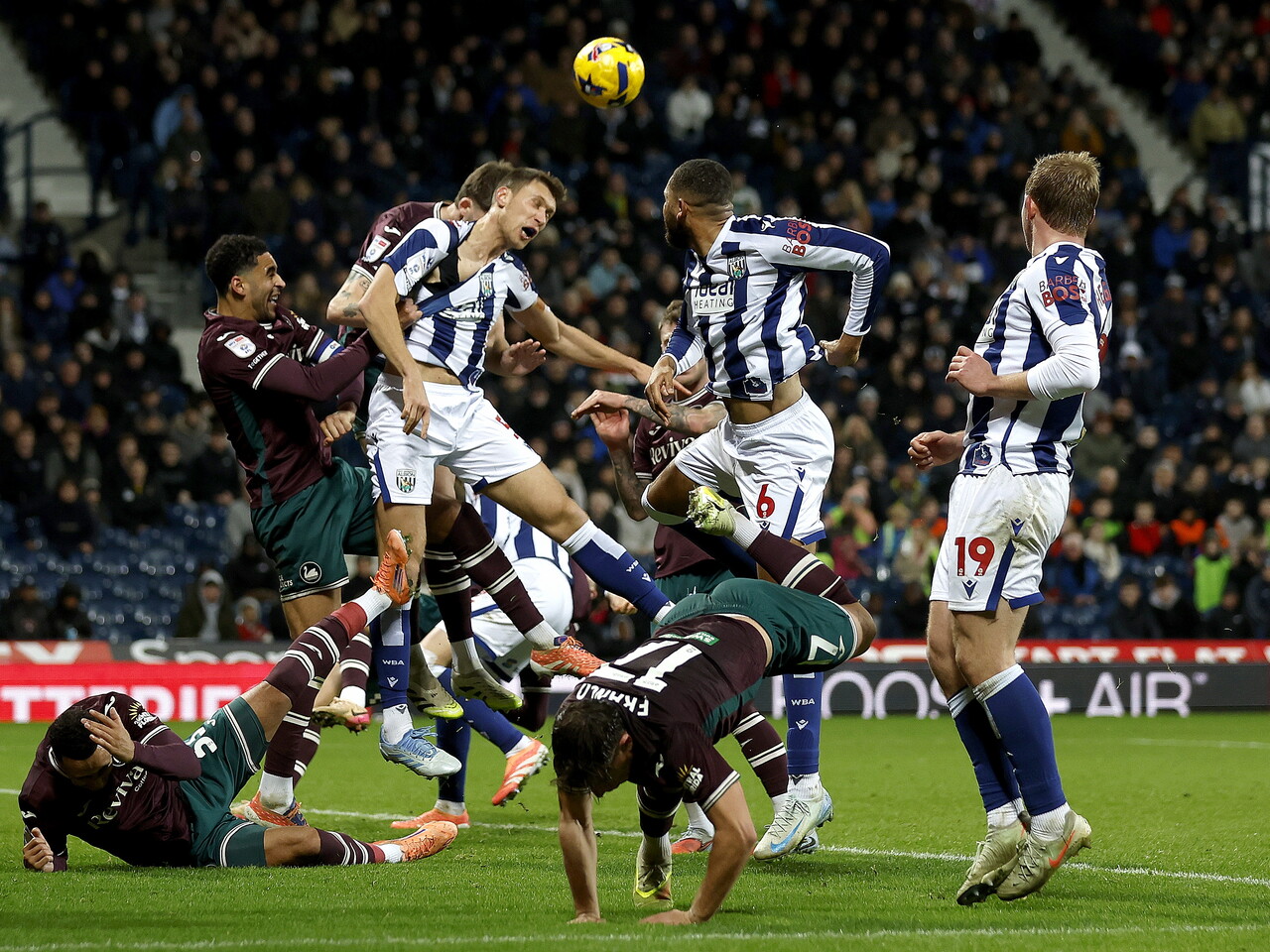 Several players battling to win the ball in the penalty area during the game between WBA and Swansea