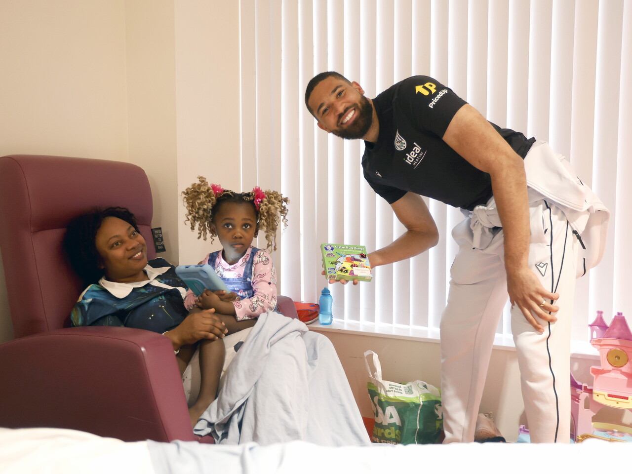 George Campbell posing for a photo with a lady and a child on a ward at Midlands Met hospital 